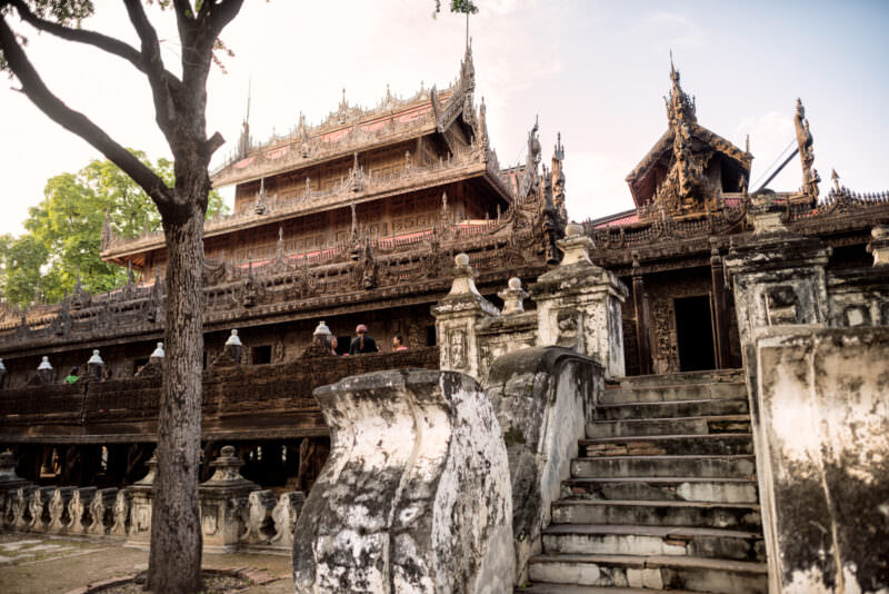 Sandstone staircases and weathered balustrade approaching multi-tiered teak facade of Shwenandaw Monastery