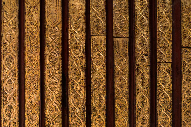 Gold-leafed teak panels inside Shwenandaw Monastery with interlocking vine-scroll and zoomorphic Konbaung carving