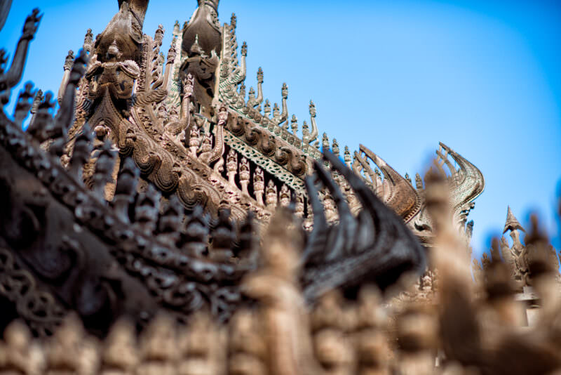 Multi-tiered pyatthat roof of Shwenandaw Monastery, dense carved teak finials and nagas sweeping across stacked diminishing tiers