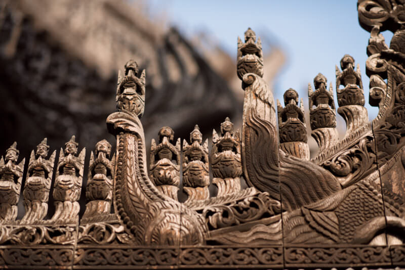 Mythical creatures and crowned figures crowding carved eave-boards of Shwenandaw Monastery, silvered weathered teak