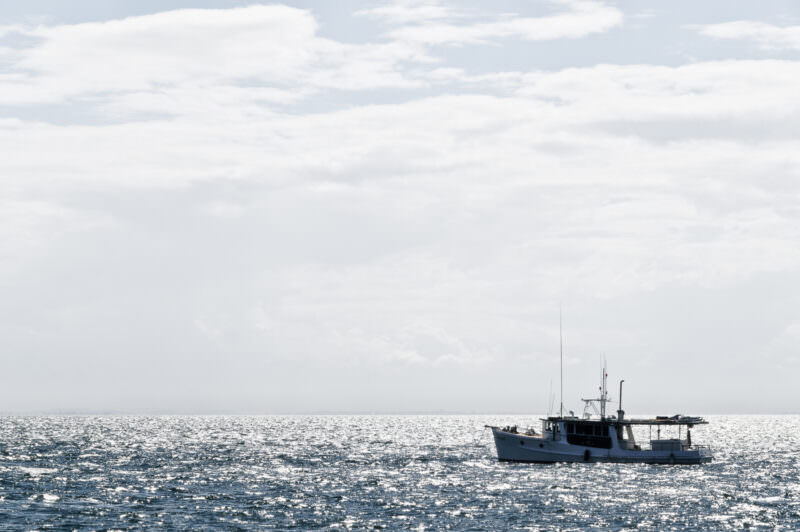 Moreton Bay Cruiser vessel silhouetted on glittering silver water under soft clouds off North Stradbroke Island