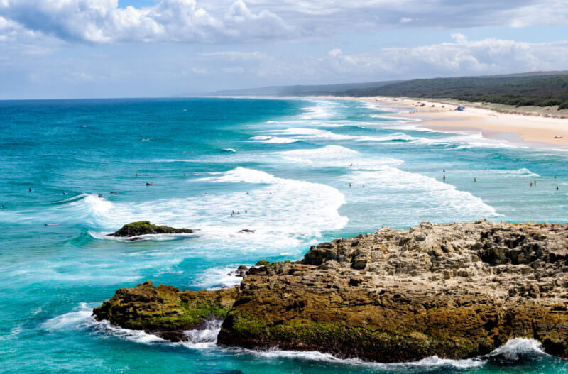 Point Lookout headland with layered volcanic rock formations in foreground, rolling Pacific surf and forested coastline stretching north
