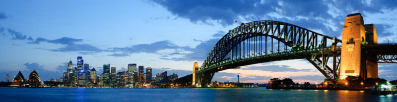 Sydney Harbour Bridge spanning Port Jackson at twilight with Circular Quay and Sydney Opera House visible