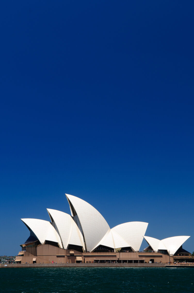 Sydney Opera House distinctive white roof shells rising from Bennelong Point along harbor waters