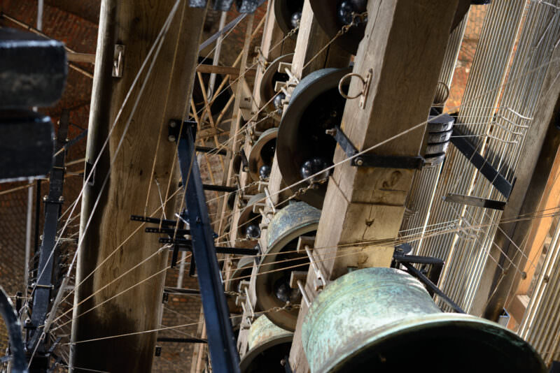 Carillon bells of the Belfry of Bruges in the timber-framed bell chamber, showing bronze bells with patina and wire linkages