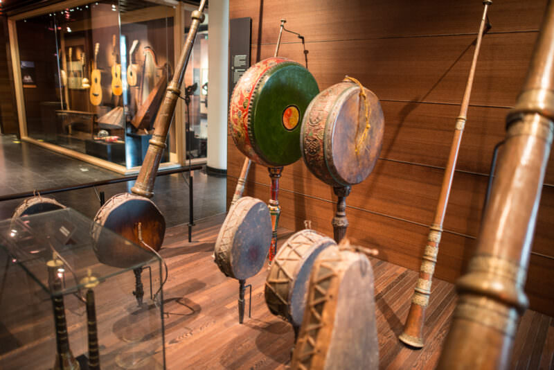 Tibetan dung chen horns in brass and pole-mounted nga drums with green and blue painted bodies on wooden platform