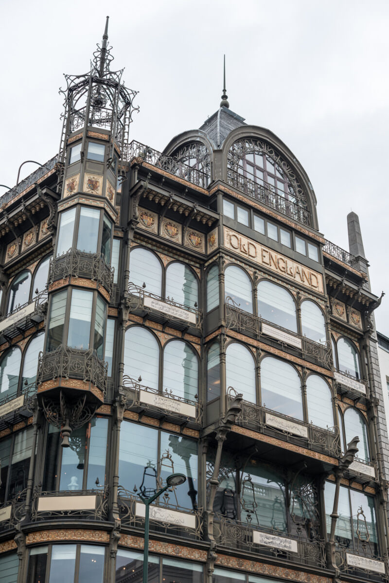 Old England building façade in Art Nouveau style, iron frame and glass curtain wall with corner turret and ornamental metalwork