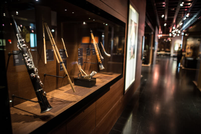 Hungarian tárogató with keyed woodwork beside triple-pipe Sardinian launeddas in glass display case