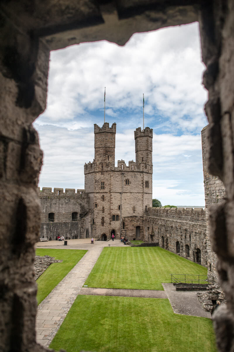 Interior courtyard framed through stone window opening at Caernarfon Castle