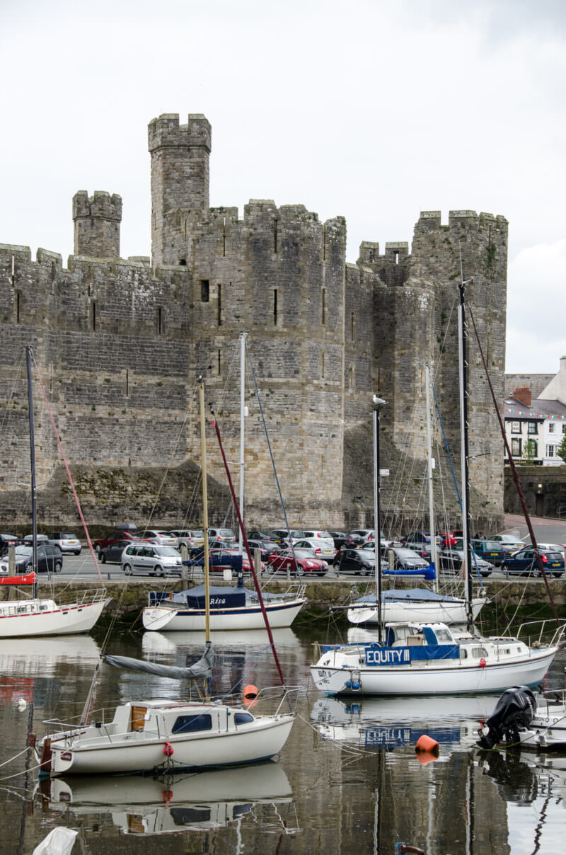 Caernarfon Castle with polygonal towers viewed across river with moored boats