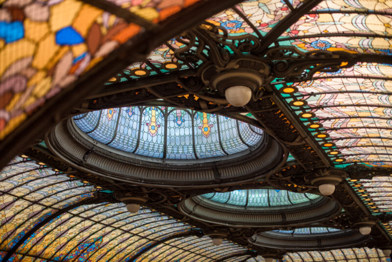 Angled perspective of Gran Hotel Ciudad de Mexico stained glass ceiling featuring eye-shaped skylights and wrought-iron ribs