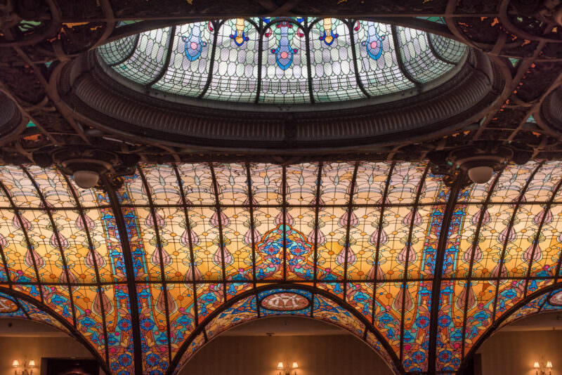 Curved stained glass panel of Gran Hotel Ciudad de Mexico showing floral medallions in blue, green, and amber tones