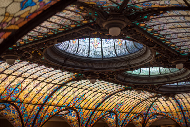 Close-up of Gran Hotel Ciudad de Mexico ceiling showing overlapping eye-shaped skylights with ornate iron frames and colored glass