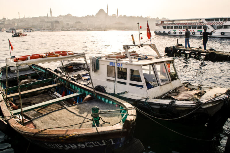 Weathered wooden fishing boats moored by Karaköy market with the Süleymaniye Mosque skyline beyond