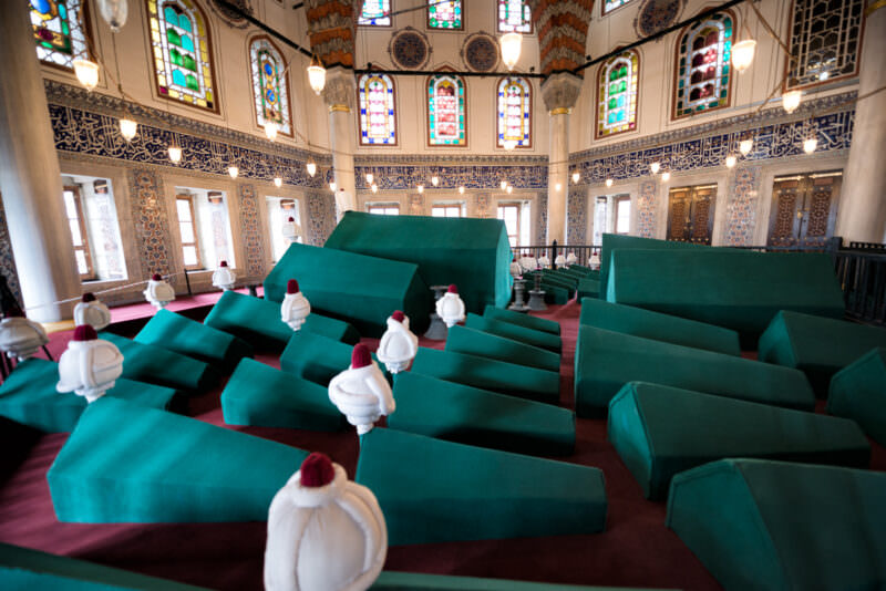Rows of green-covered sarcophagi topped with turban finials inside the Tomb of Sultan Murad III