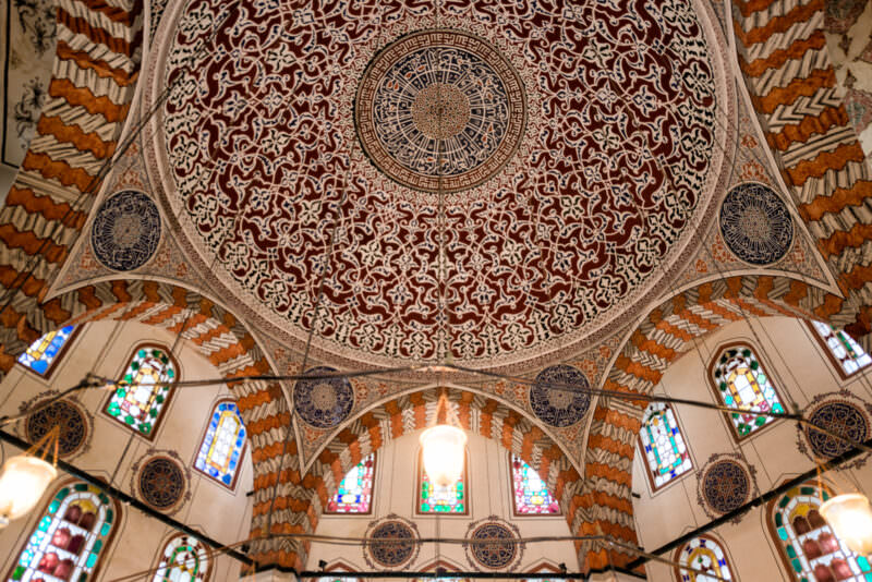 Hexagonal domed ceiling of the Tomb of Sultan Murad III with Kufic calligraphy over stained-glass windows