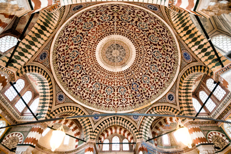Richly patterned dome of the Tomb of Sultan Selim II viewed from below amid tiled arches and windows