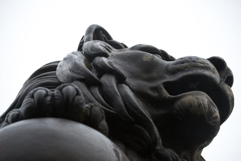 Close-up of the cast-iron lion statue atop the Lion's Mound, showing detailed mane sculpting and weathered metal surface