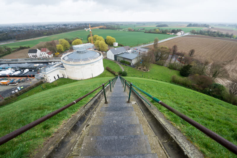 Staircase descending the Lion's Mound toward the white Panorama rotunda and green farmland beyond