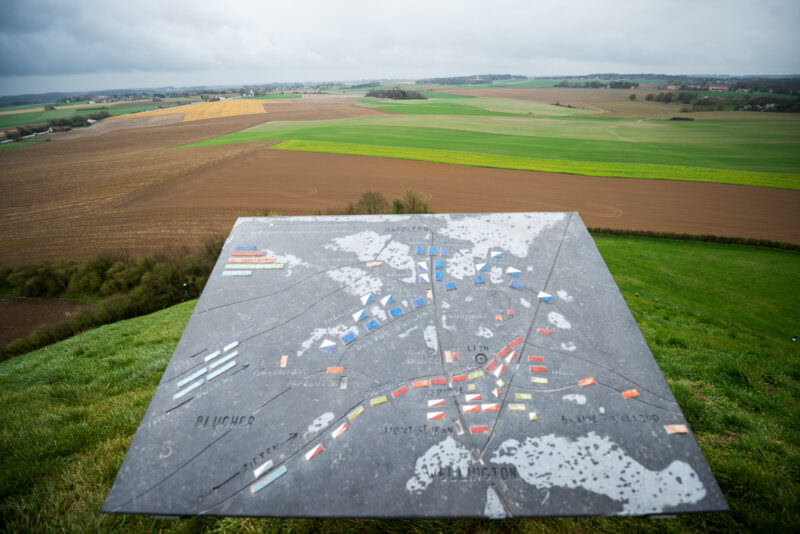 Orientation map atop the Lion's Mound showing troop positions in colored blocks, overlooking the farmland of Waterloo