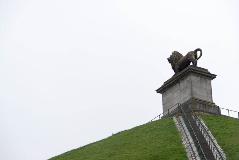 Lion's Mound with stone pedestal and lion statue at summit, green slope and staircase ascending from foreground