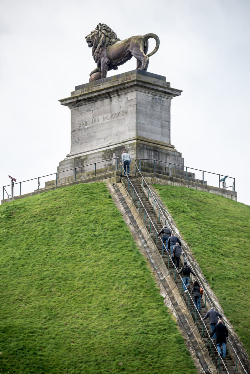 Lion's Mound viewed from below, showing visitors ascending the staircase toward the lion statue and pedestal