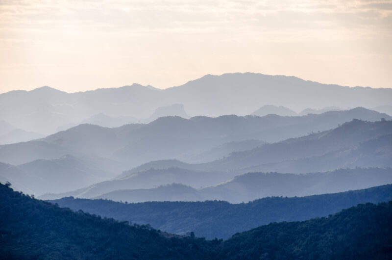 Layered mountain ridges in shades of blue and green receding into atmospheric haze