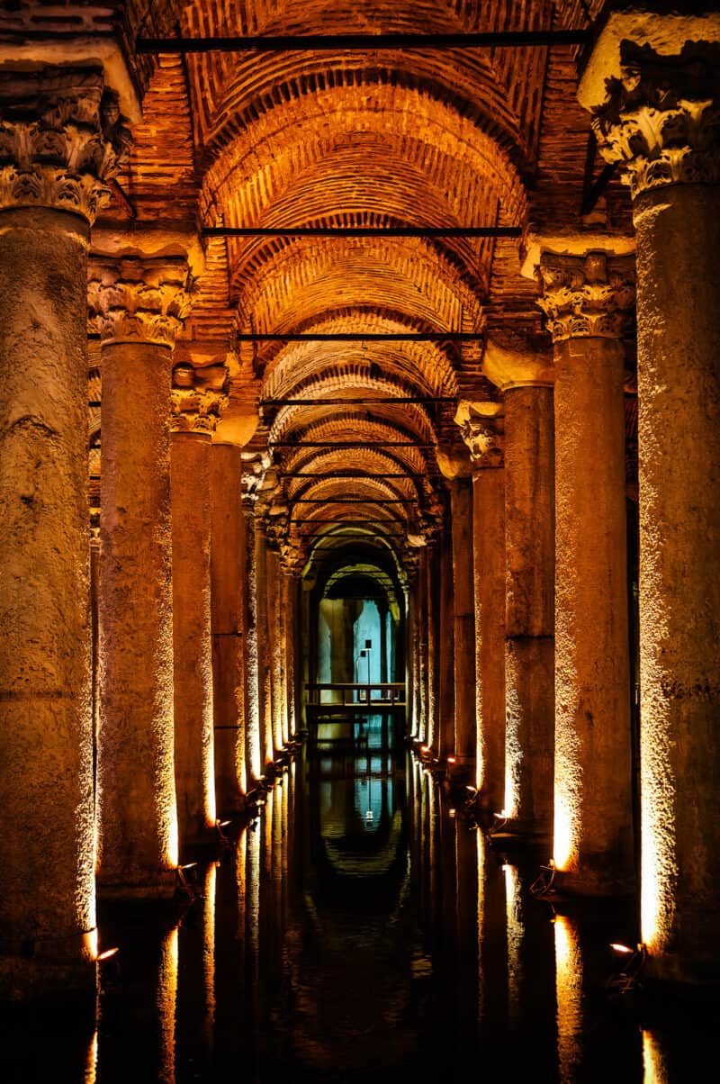 Long view of arched brick ceilings and lit marble columns receding into the Basilica Cistern