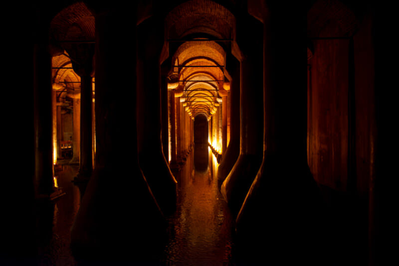 Symmetrical view down a torch-lit column corridor deep inside the Basilica Cistern