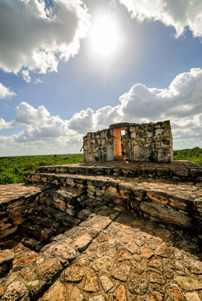 Ruined Maya chamber atop Ek' Balam's Acropolis, with Yucatán jungle stretching to the horizon under a sunlit sky