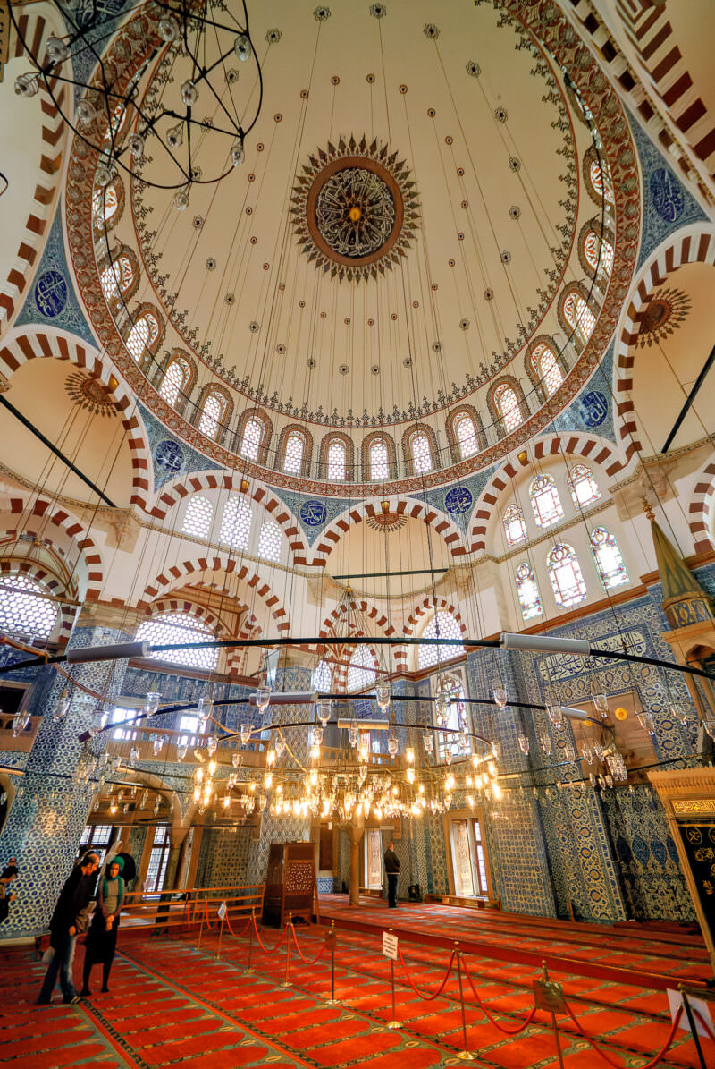 Wide-angle view of Rustem Pasha Mosque's painted dome and tiled arches with a central sunburst medallion