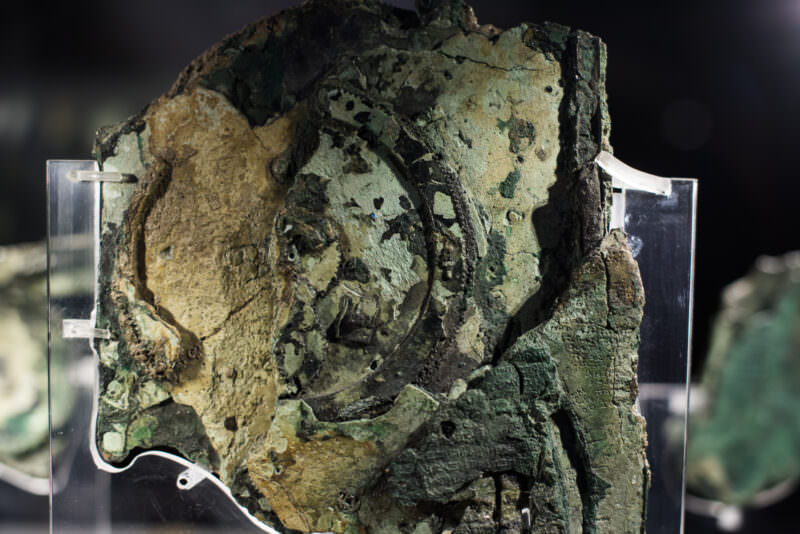 Reverse side of Antikythera Mechanism Fragment A displaying exposed gear trains, corroded bronze surfaces in shades of green and tan