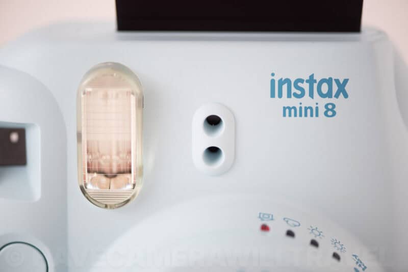 Close-up of the Instax Mini 8's flash and viewfinder above its logo and exposure light indicators