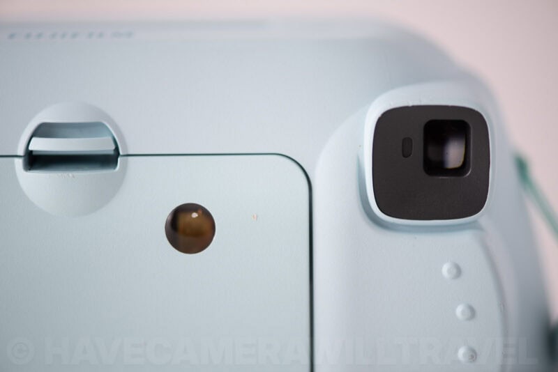 Close-up of the Instax Mini 8's small square viewfinder and light sensor on its front panel