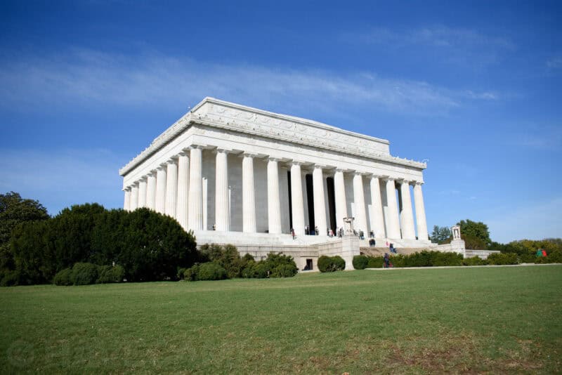Lincoln Memorial exterior viewed from the lawn, its colonnade and pediment under blue sky