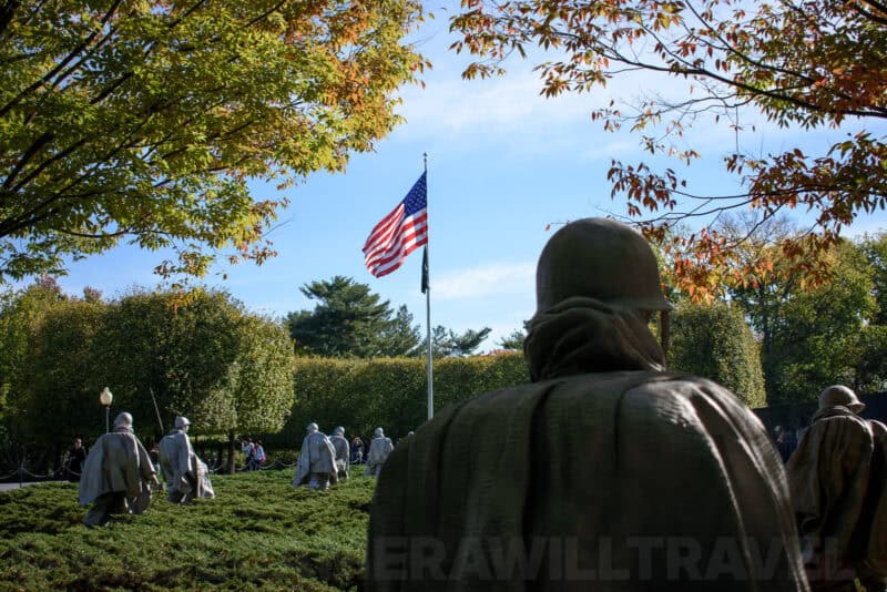 Korean War Veterans Memorial statues among trees with an American flag flying beyond