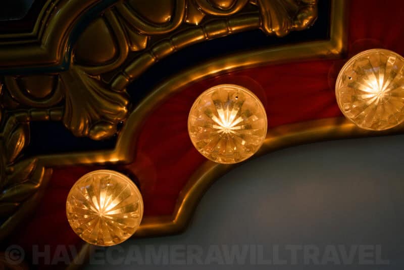 Close-up of glowing globe light fixtures set against a red and gold carousel canopy