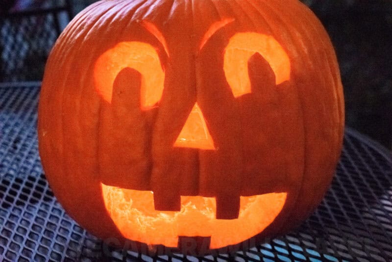 Glowing carved jack-o'-lantern with a grinning face lit from within at night