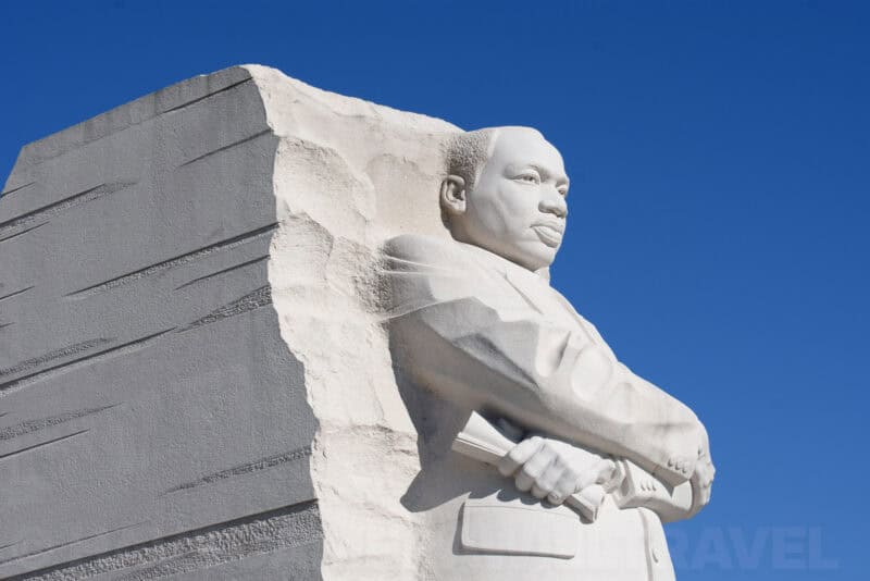 Martin Luther King Jr Memorial statue in profile, arms crossed, carved from pale granite