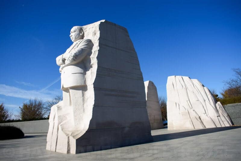 Martin Luther King Jr Memorial Stone of Hope statue emerging from split granite against blue sky