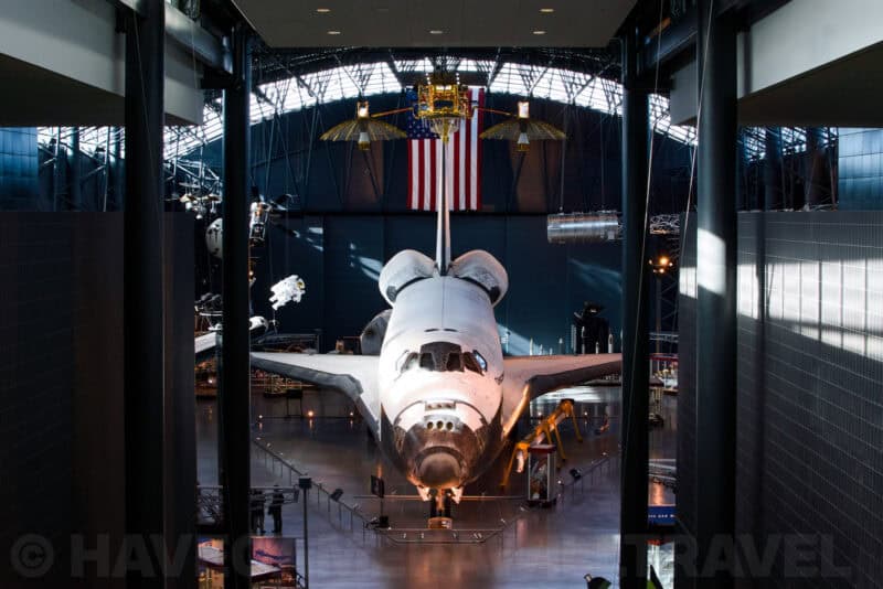 Space shuttle Discovery on display beneath an American flag inside the Udvar-Hazy Center hangar