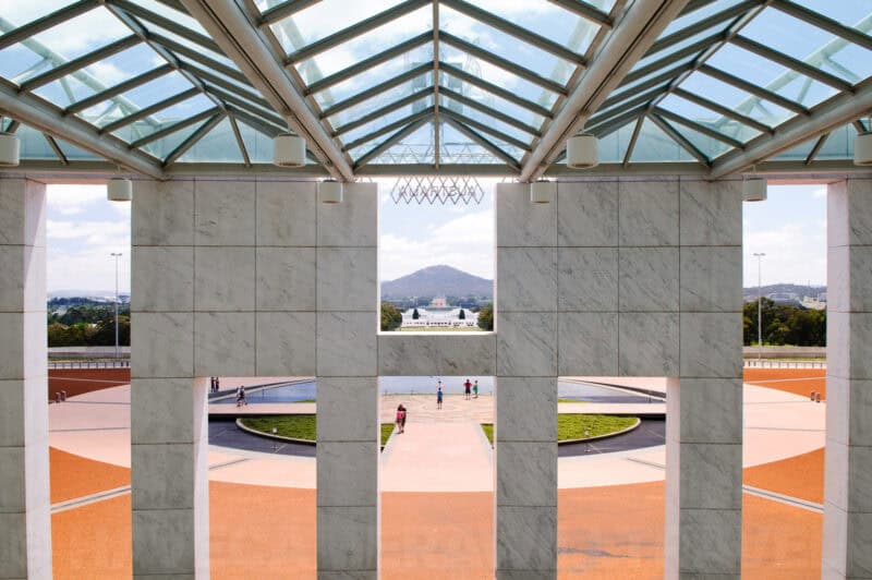 View through the glass-roofed forecourt of Parliament House in Canberra toward Mount Ainslie