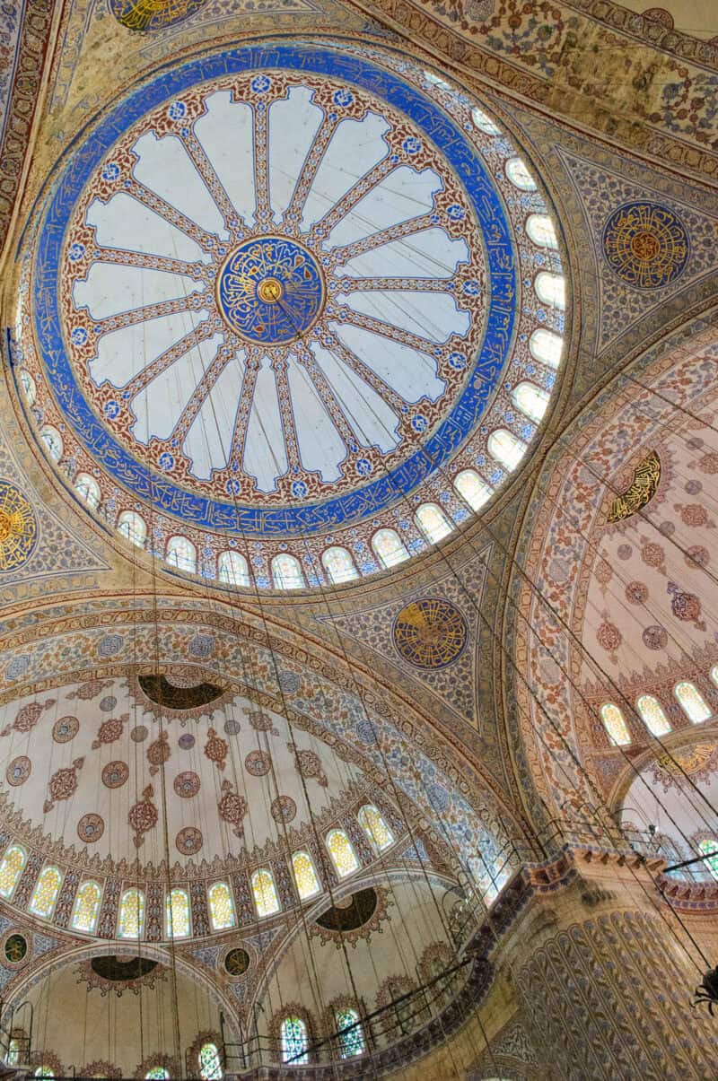 Ornate painted domes and stained glass windows inside the Blue Mosque in Istanbul