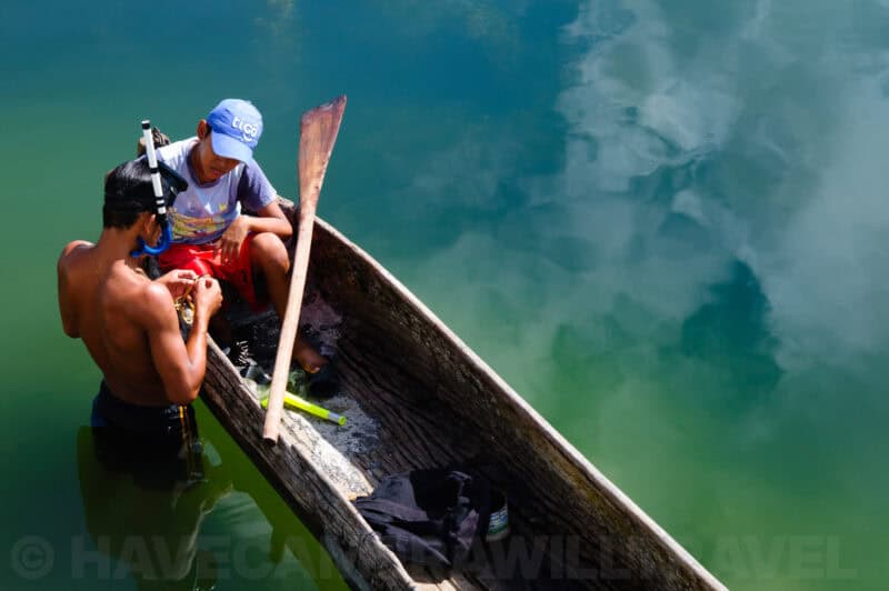 Two boys preparing fishing gear from a wooden canoe on the lake at Flores, Guatemala