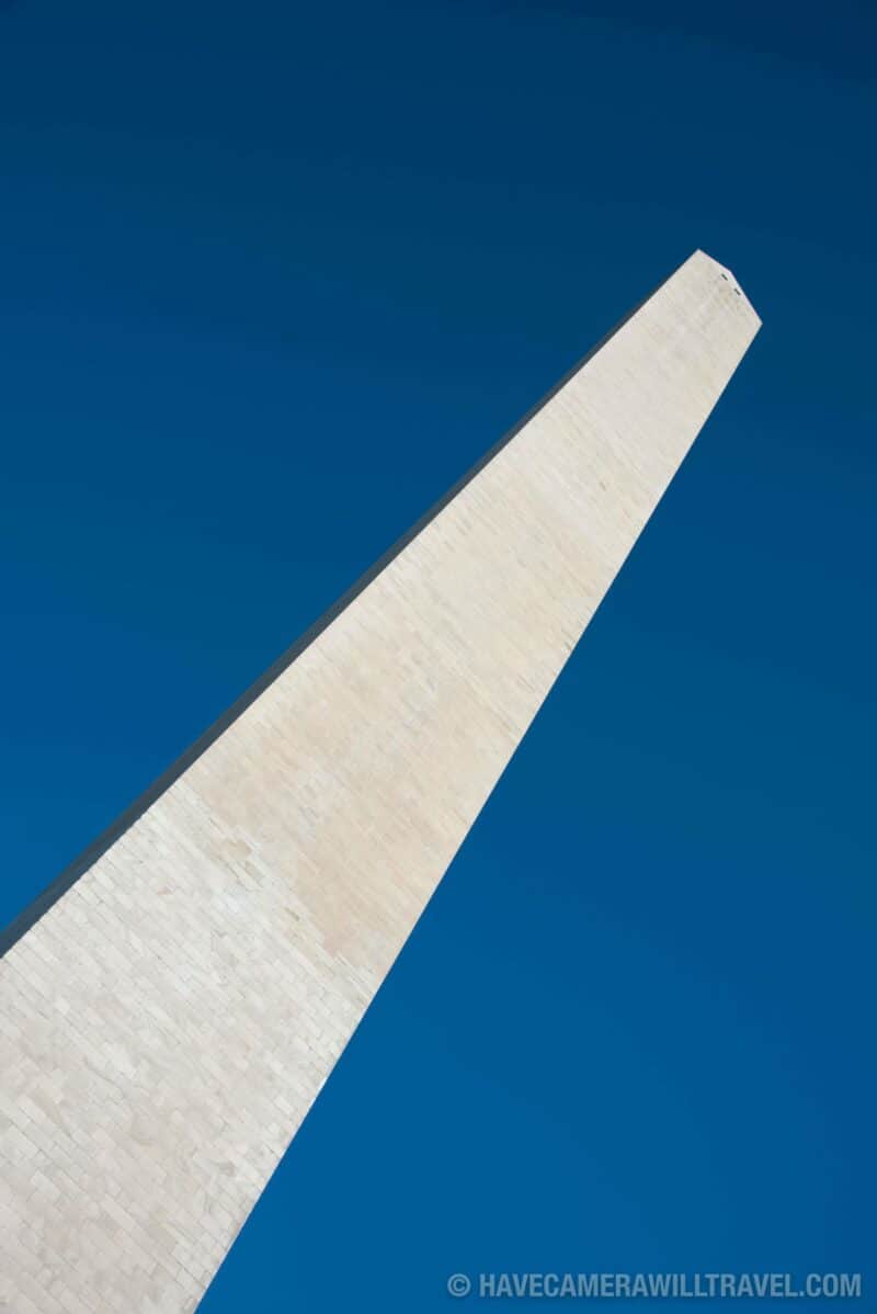 Diagonal close-up view of the Washington Monument's stone edge against blue sky