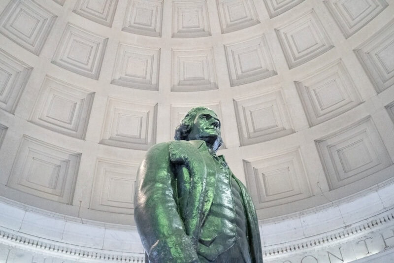 Green-patinated statue of Thomas Jefferson viewed from below against the memorial's coffered dome