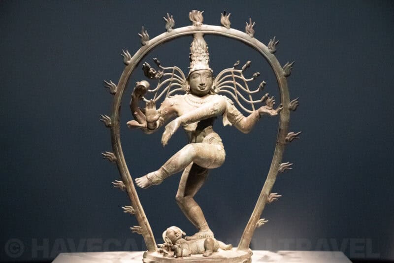 Bronze statue of Shiva Nataraja dancing within a flaming ring against a dark background