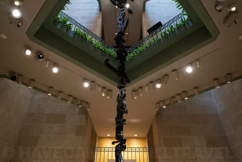 Skylit atrium with hanging modern sculpture and living green wall above a museum stairwell