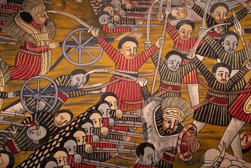 Close-up of an Ethiopian battle mural depicting soldiers with rifles and cannon wheels