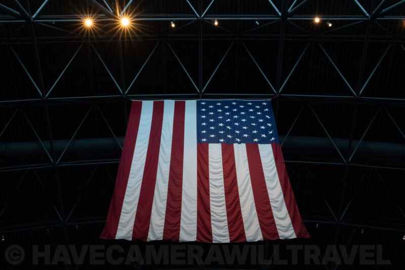 American flag hung inside a geodesic dome structure lit by spotlights with starburst effect